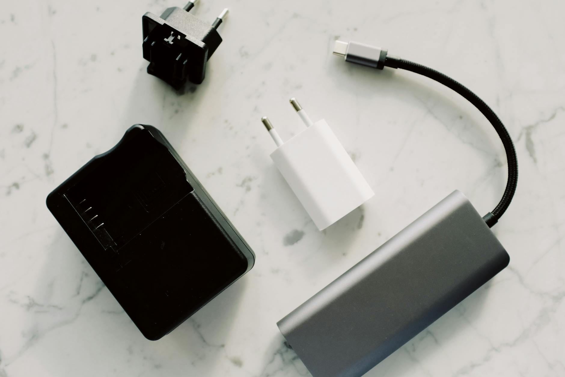 A collection of electronic adapters and cables on a marble surface, showcasing tech essentials.