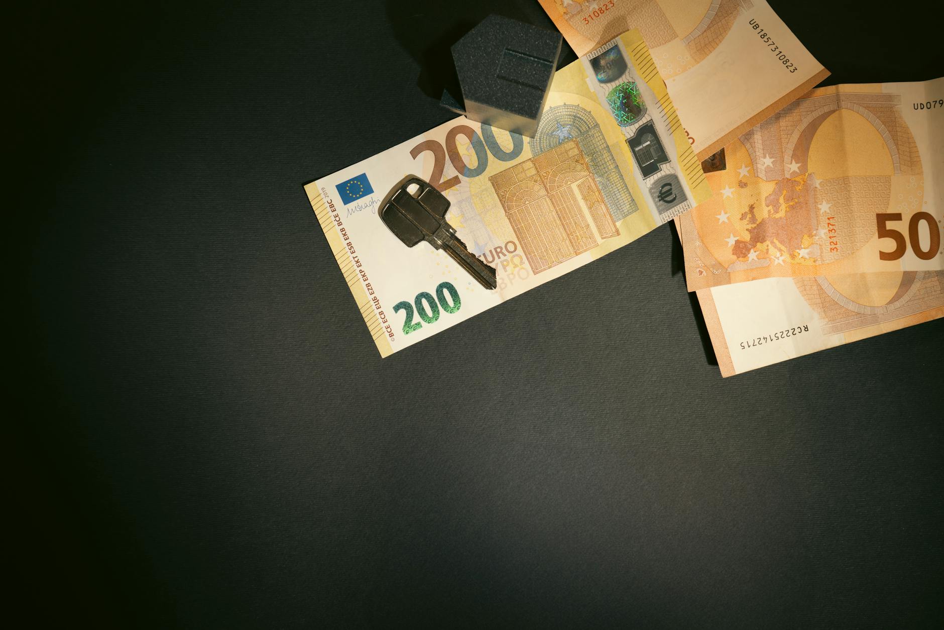 Flat lay of a house key on Euro bills representing real estate investment and finance.