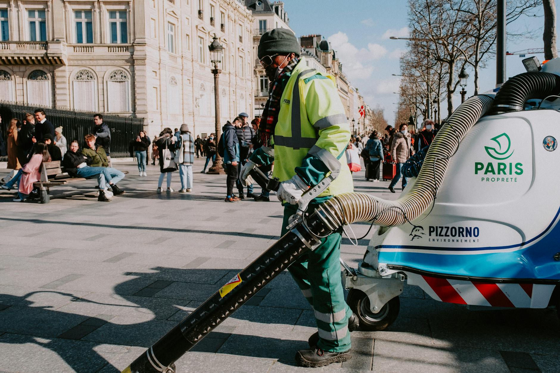 Paris street cleaner operating equipment, showcasing urban cleanliness amidst city life.