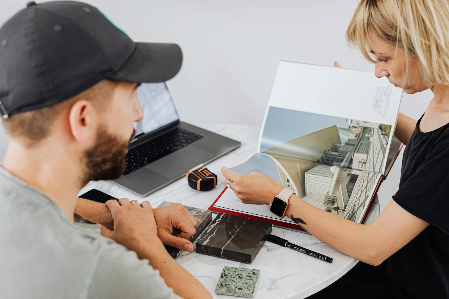 Two interior designers discussing architectural plans in an office setting.