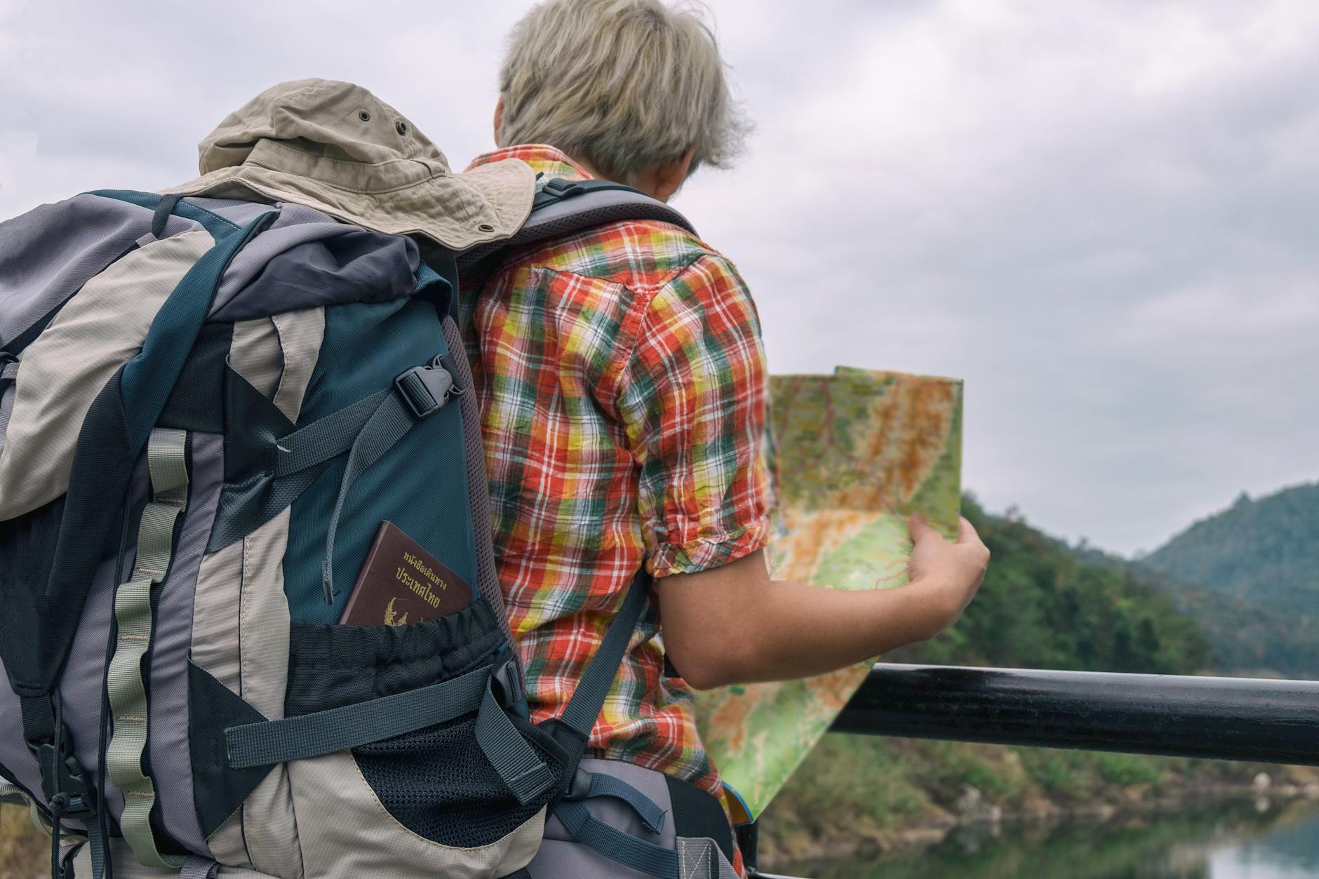 A backpacker examining a map against a scenic outdoor landscape. Adventure awaits.