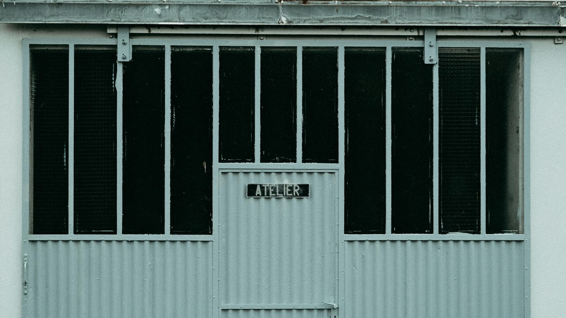 Close-up of an industrial style workshop door with a metal 'Atelier' sign.