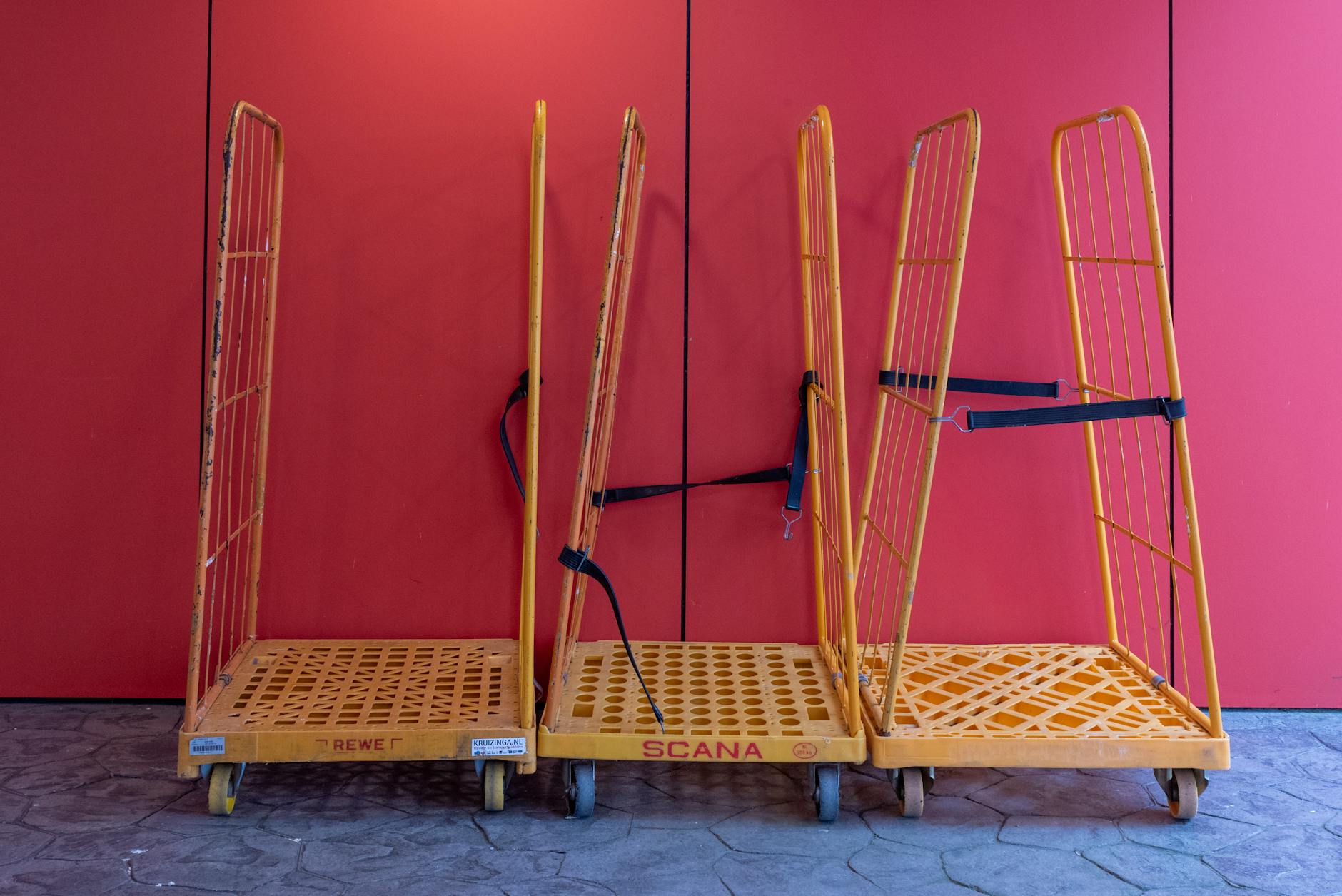 A row of yellow warehouse trolleys against a vibrant red wall.