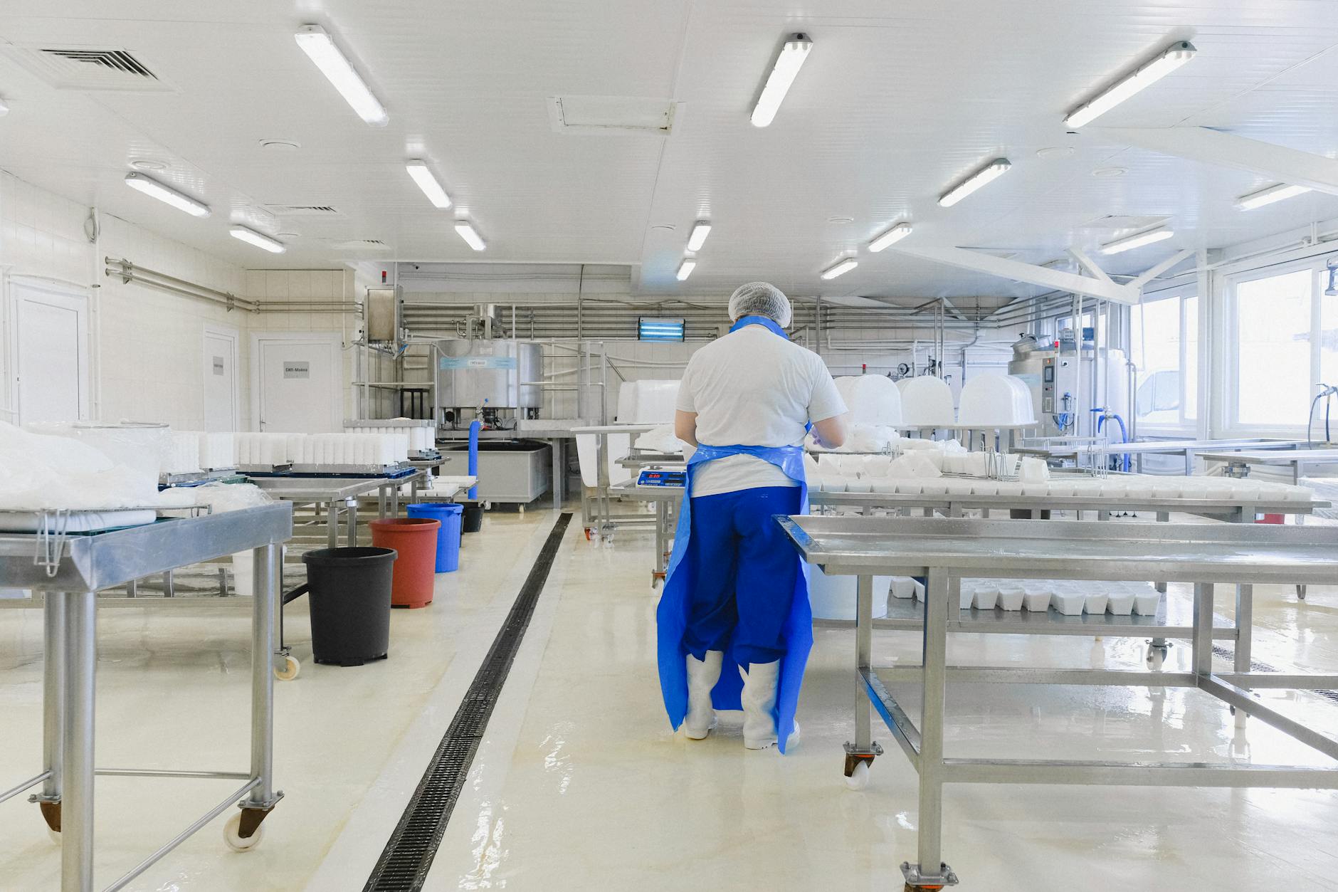A person wearing protective clothing working in a bright, sterile laboratory environment.